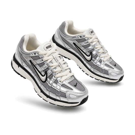 Nike P-6000 color plateado — par de tenis en vista 3D, fondo blanco